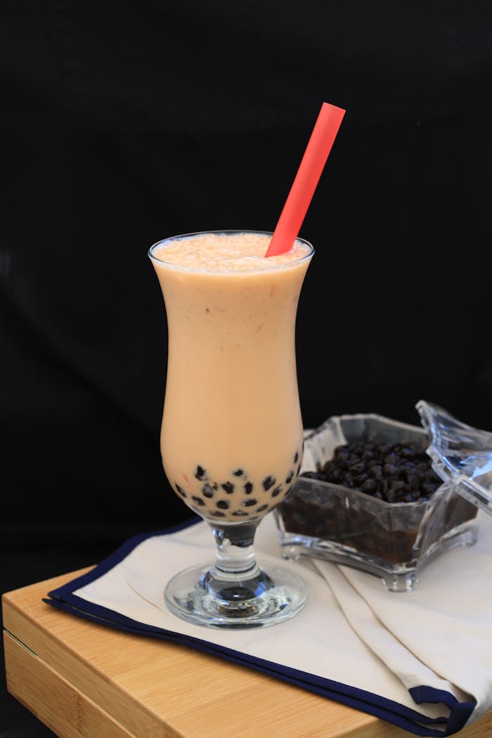 A refreshing glass of boba milk tea with tapioca pearls and a pink straw.